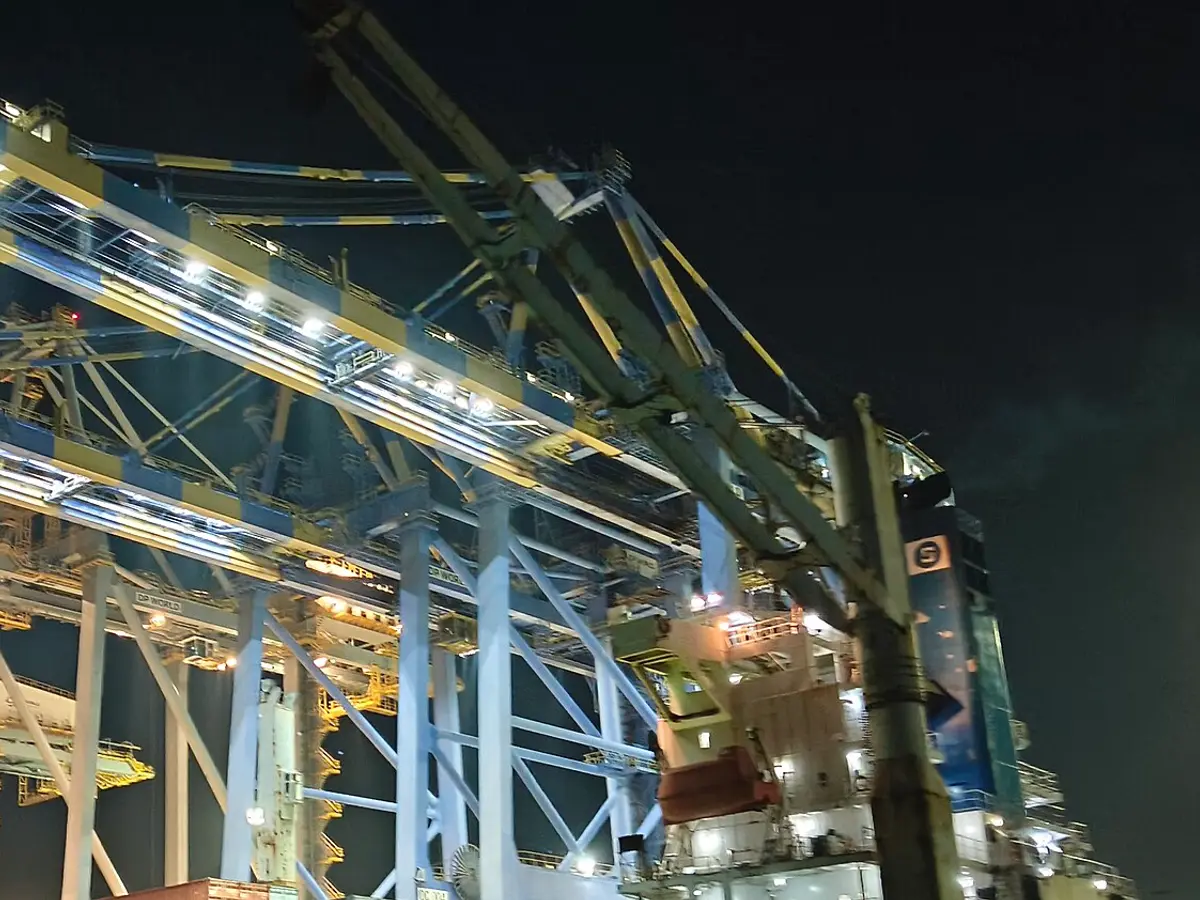 Gantry cranes loading a container ship at night at the International Container Transshipment Terminal in Kochi, India